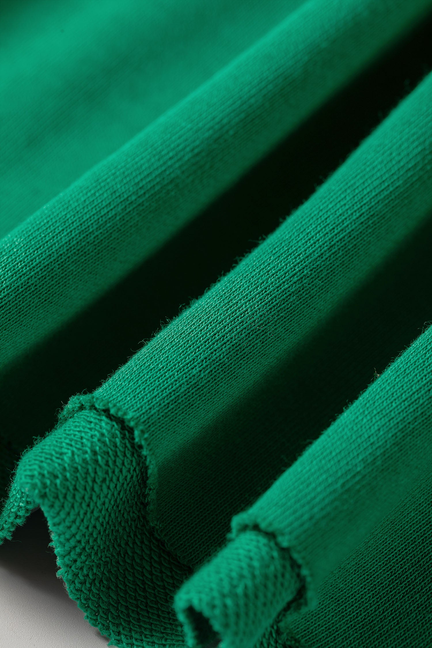Raw edge hem detail on bright green hoodie and pants set