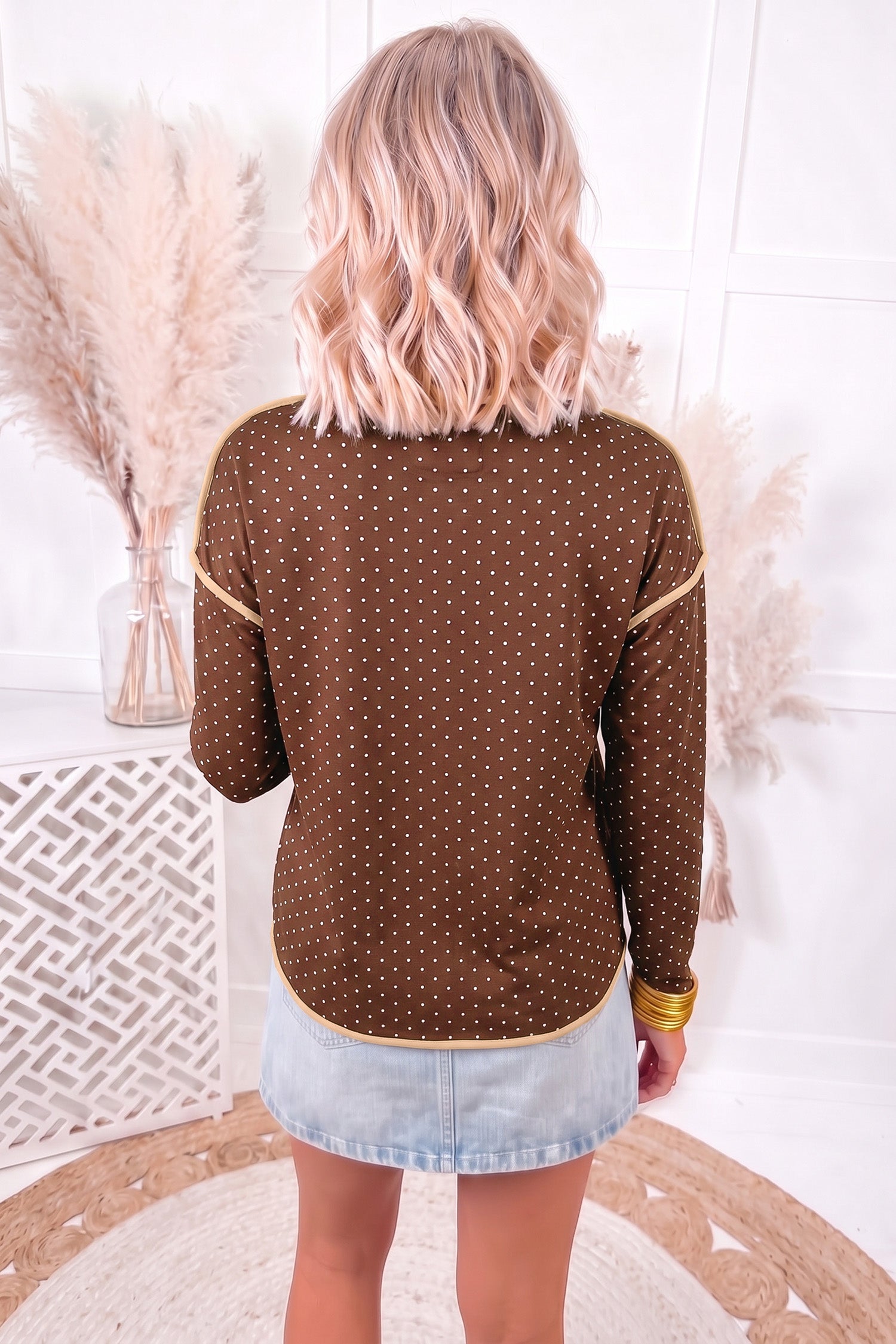 Back view of brown pin dot long sleeve shift top with tan trim on shoulders and curved hem