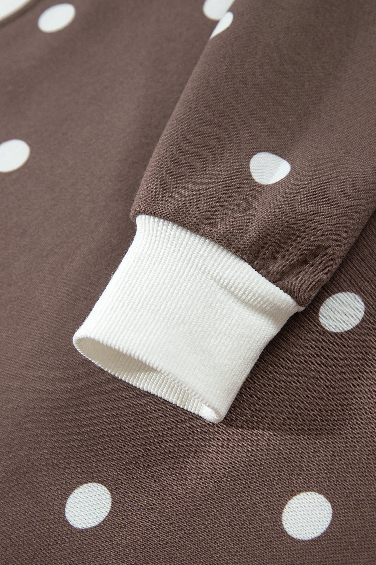 White ribbed sleeve cuff on brown polka dot top, close-up