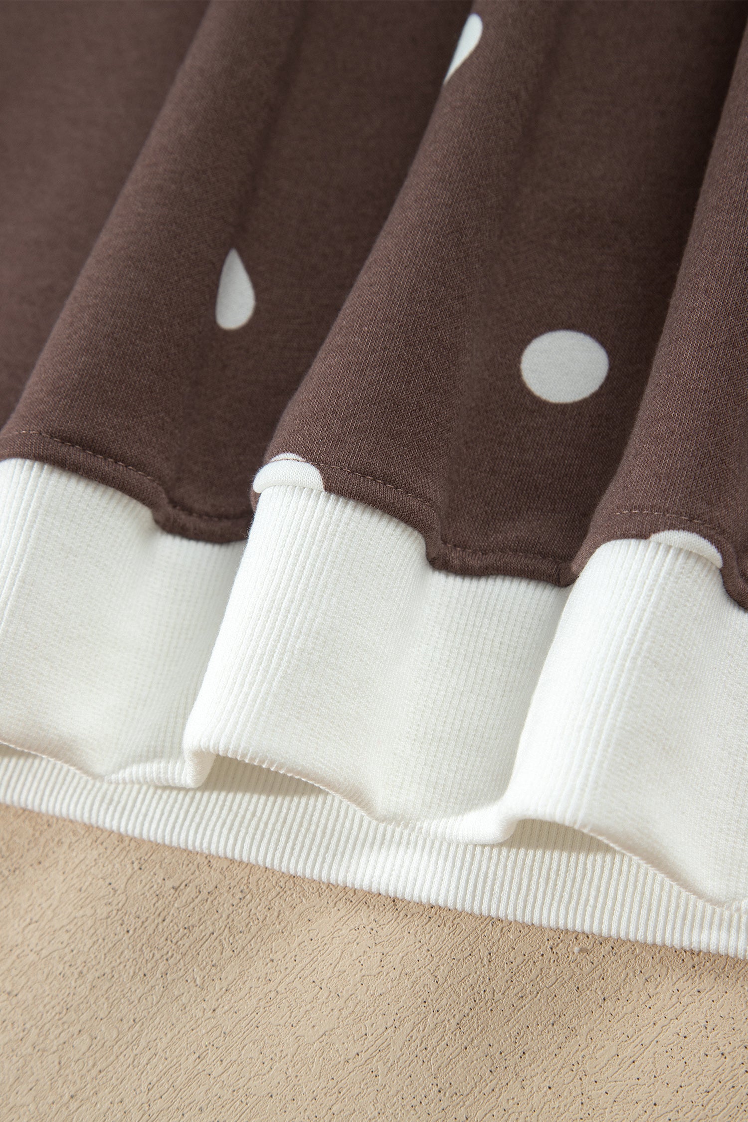 White ribbed hem band on brown polka dot top, close-up