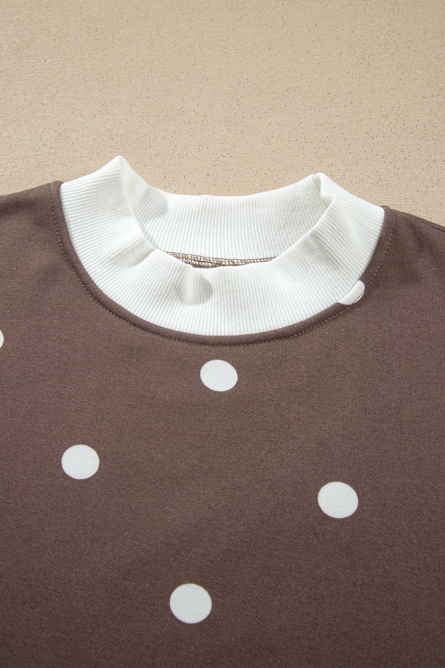 Contrast white ribbed crew neckline on brown polka dot top
