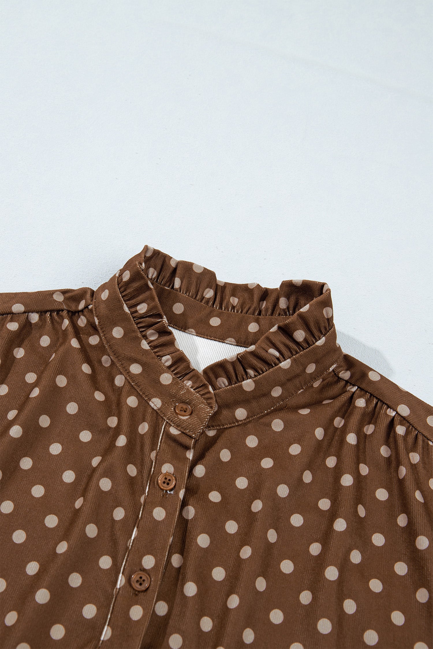 Close-up of ruffled stand collar and button placket on brown polka dot dress