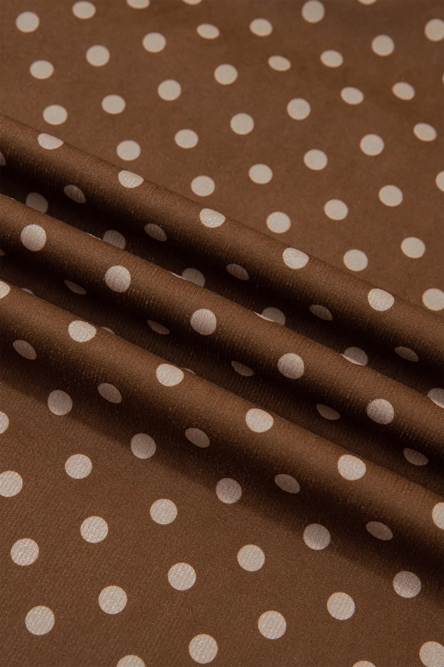 Close-up of smooth brown fabric with cream polka dot print