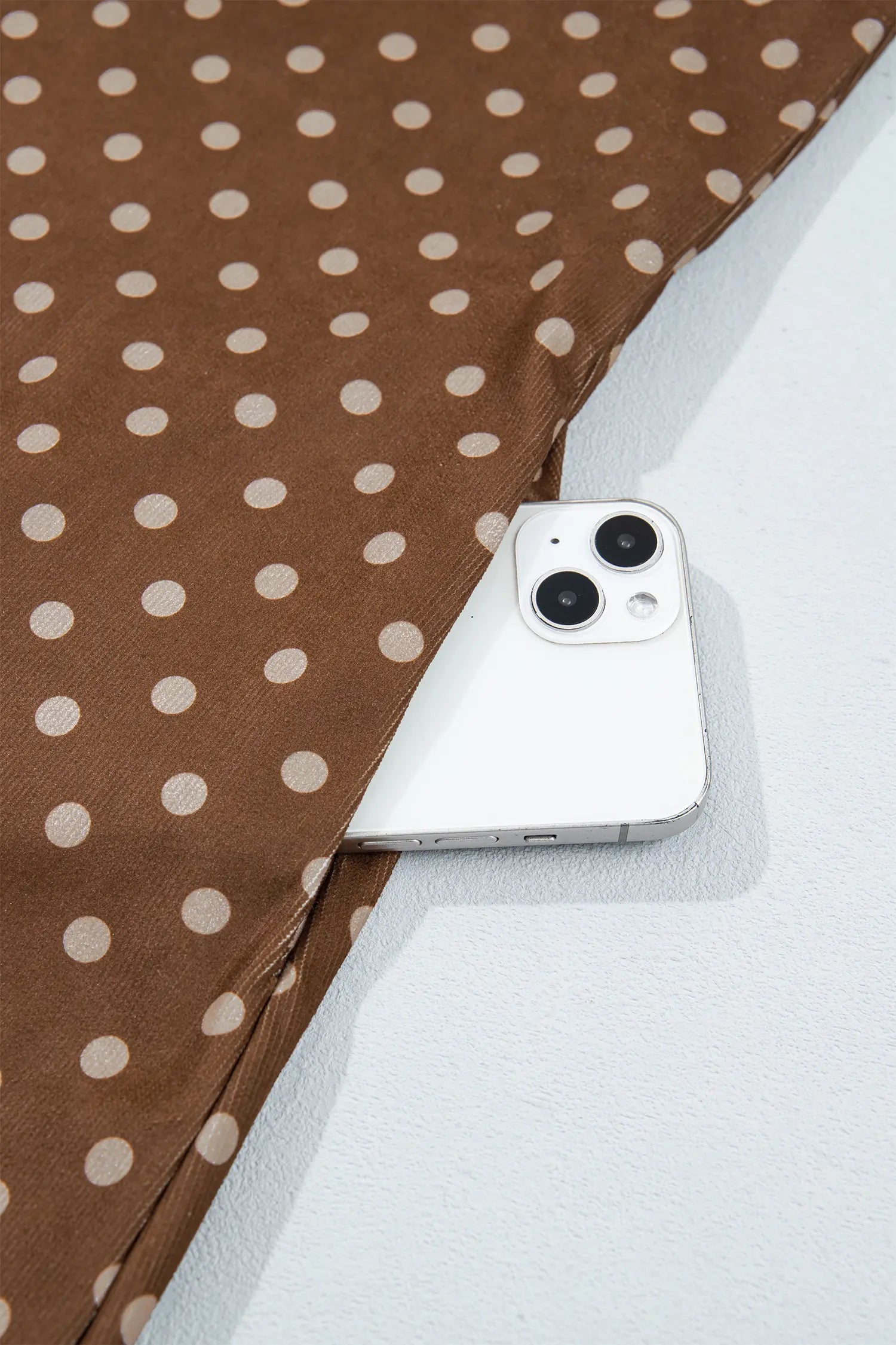 Side seam pocket holding a phone on brown polka dot shift dress