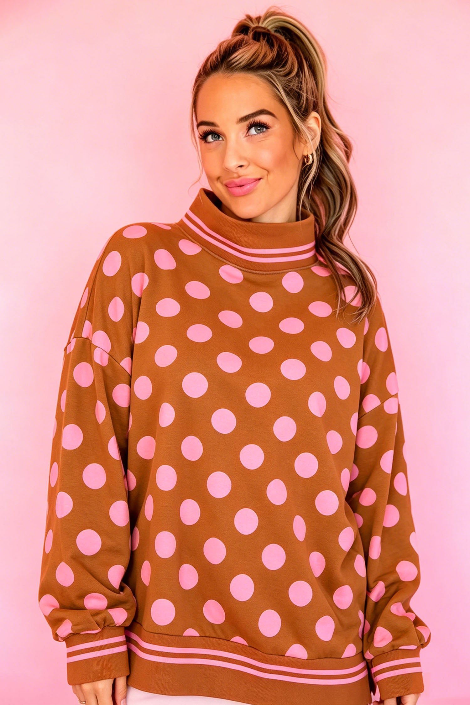 Woman in brown oversized sweatshirt with pink polka dots and striped ribbed trim