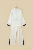White pajama set with black lace trim on cuffs and hem.