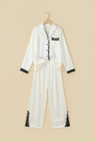 White pajama set with black lace trim on hanger.