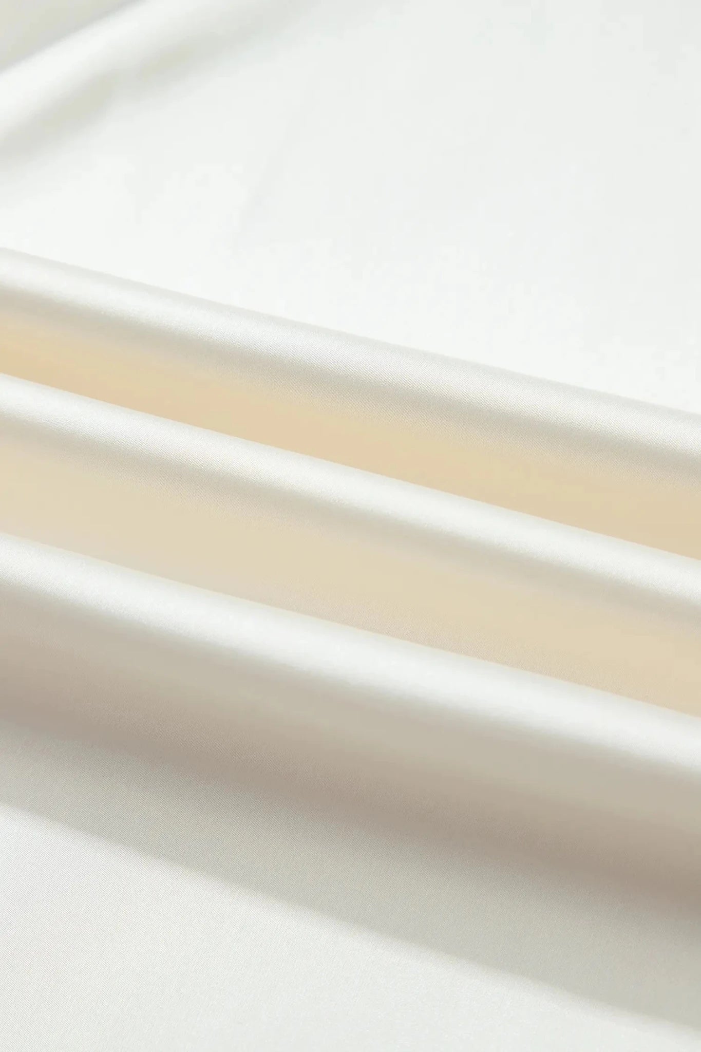 A close-up of a smooth, off-white or cream-colored material with soft folds and a matte finish.