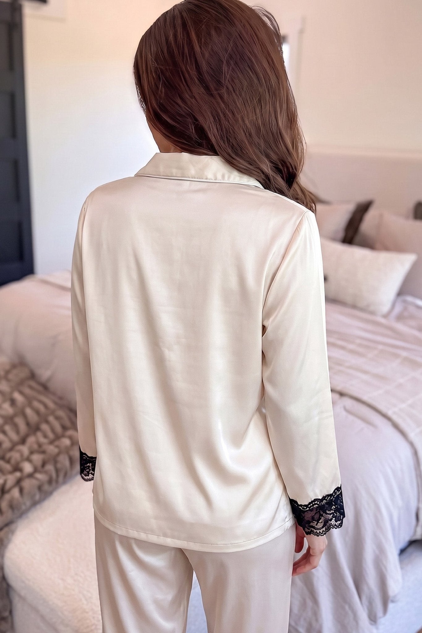 Back view of woman in cream satin pajamas with black lace cuffs.