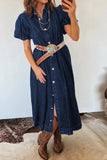 Woman wearing a denim dress with a belt and cowboy boots, taking a mirror selfie.