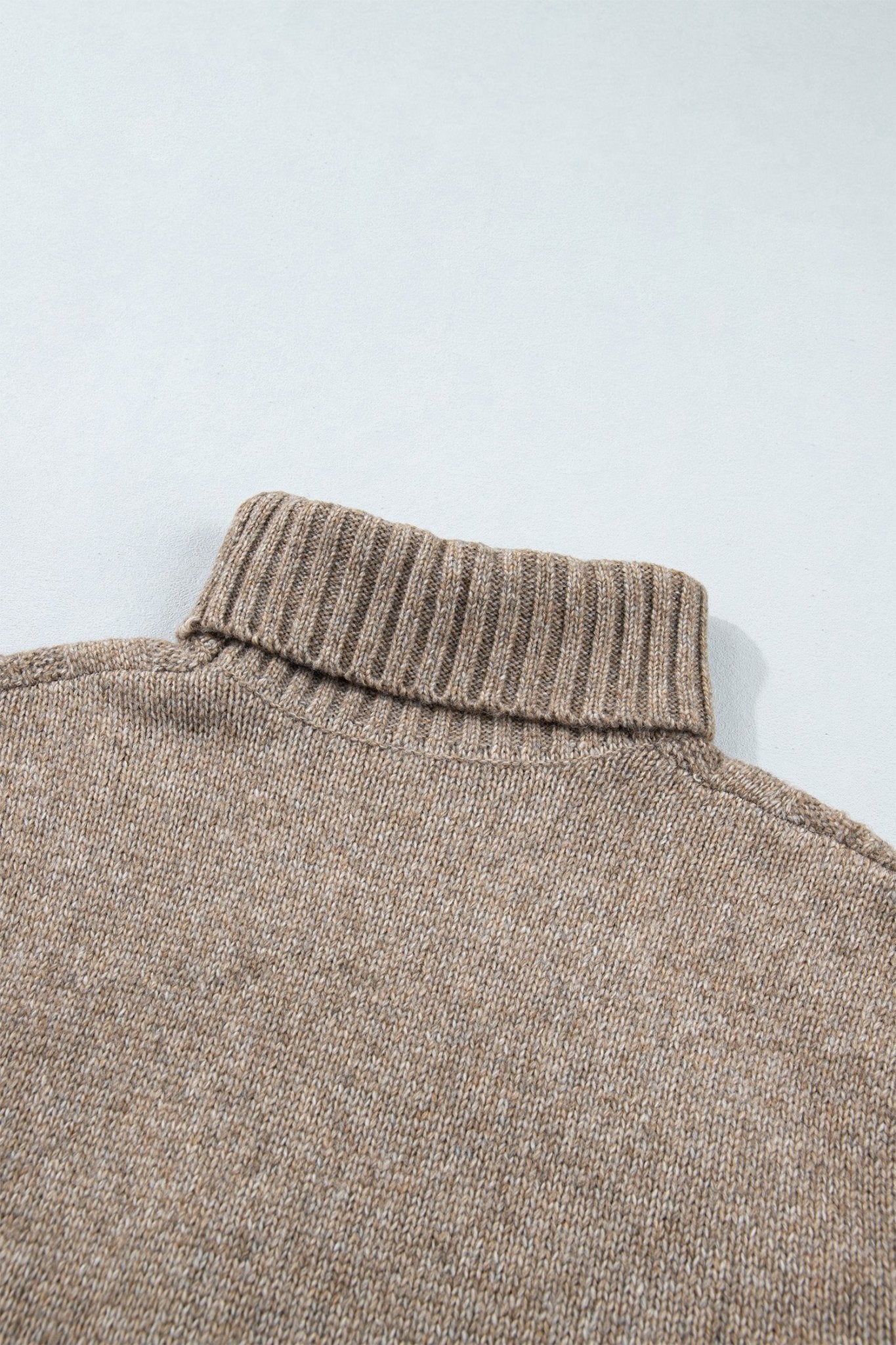 Close-up of warm taupe-brown ribbed turtleneck sweater collar and upper chest.