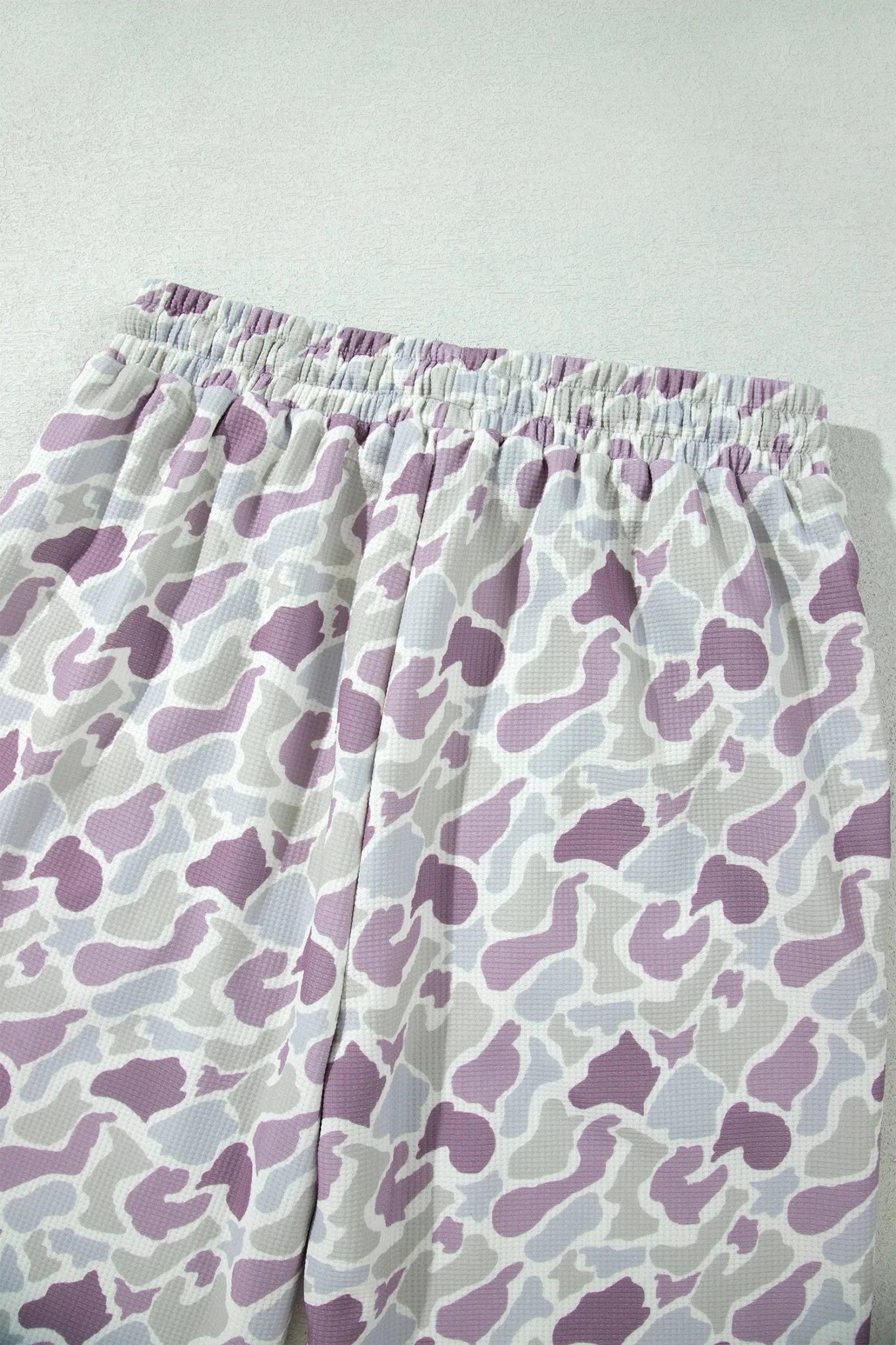Purple and gray abstract camouflage shorts with an elastic waistband on white.
