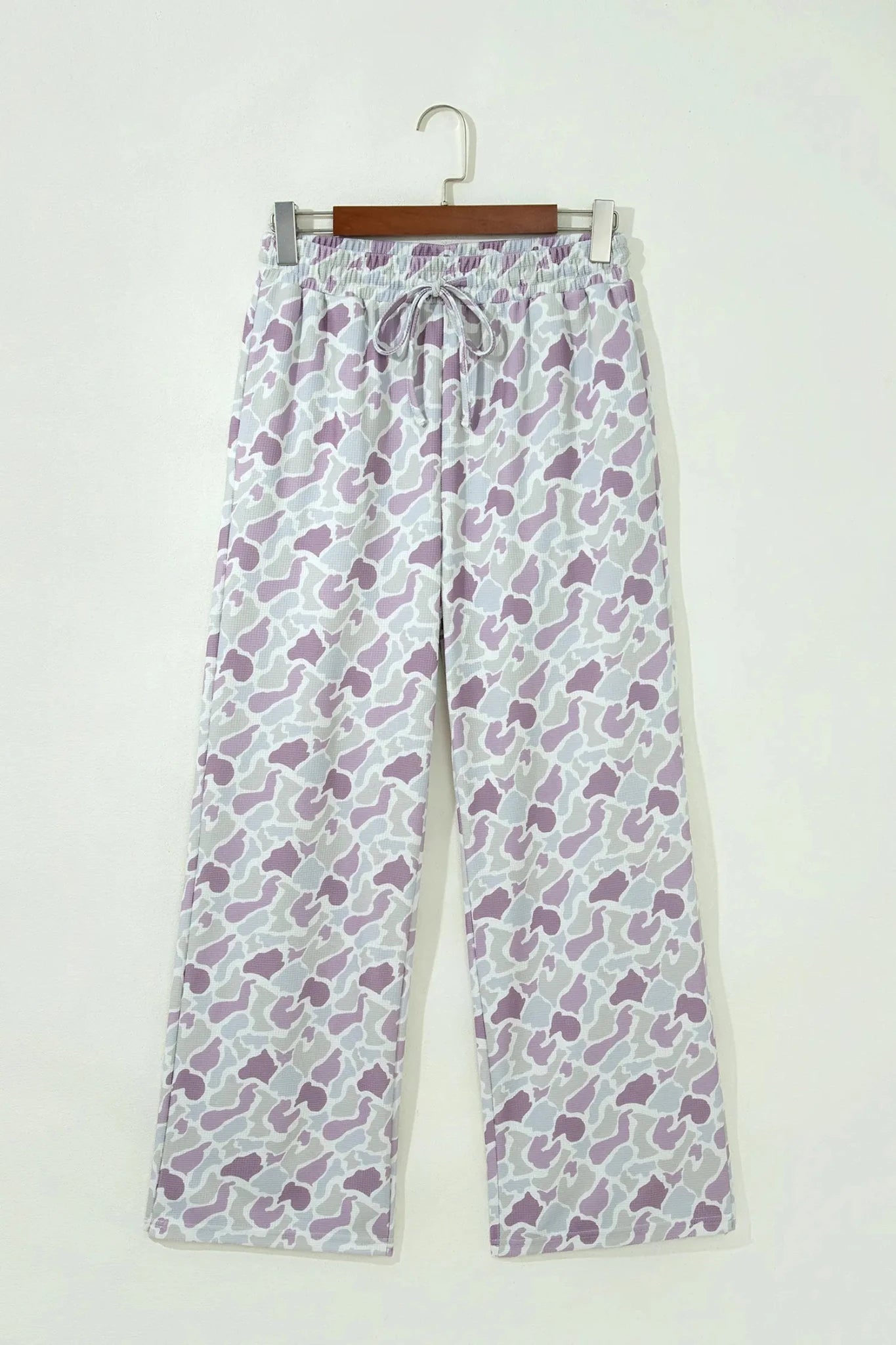 Purple and white abstract wide-leg lounge pants on a wooden hanger.