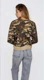 Person wearing a camouflage sweater and light blue jeans on a white background