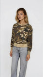 Woman wearing a camouflage sweater and jeans on a white background