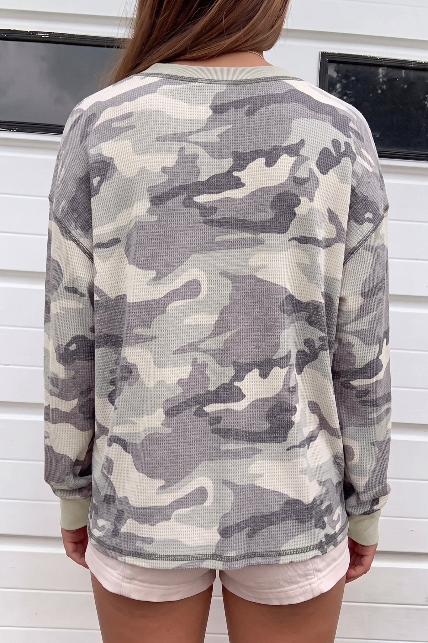 Back view of person in gray-beige camo waffle-knit sweatshirt and pink shorts.

