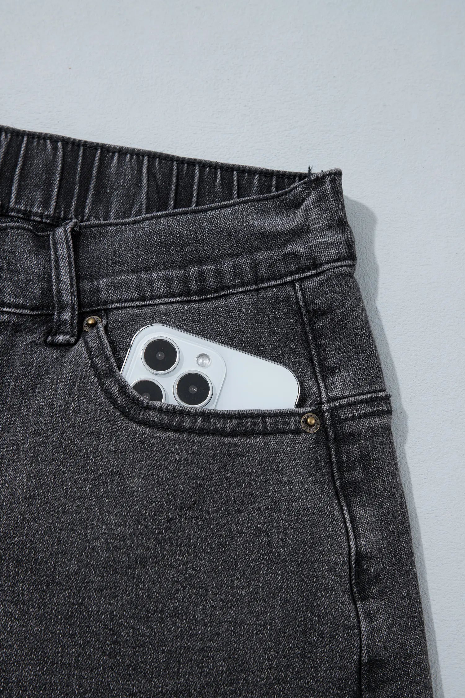 Close-up of front pocket holding a phone on carbon grey jeans