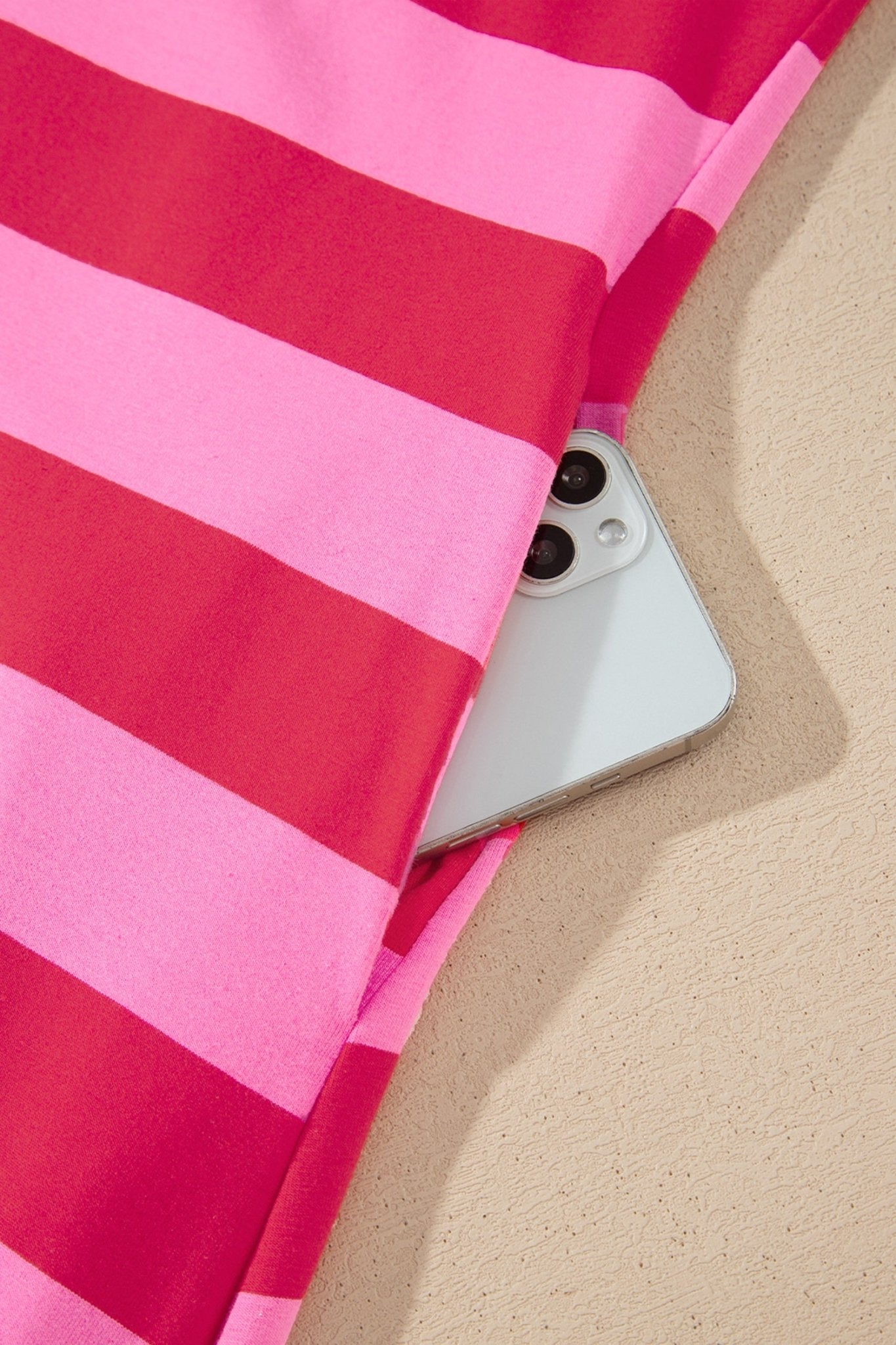 Close-up of pink and red striped fabric with a silver smartphone.