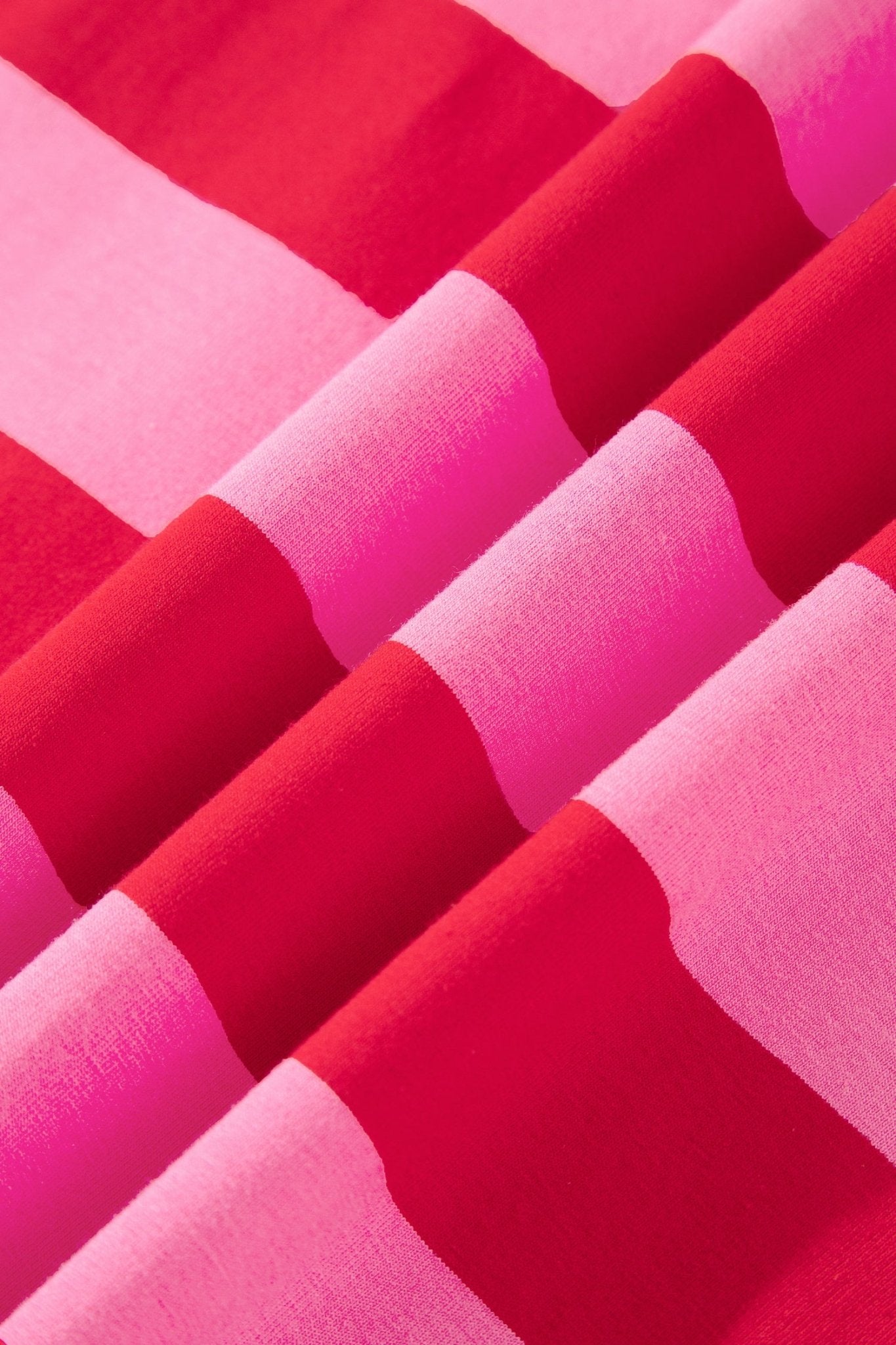 A close-up of draped fabric with alternating wide bands of bright pink and deep red.