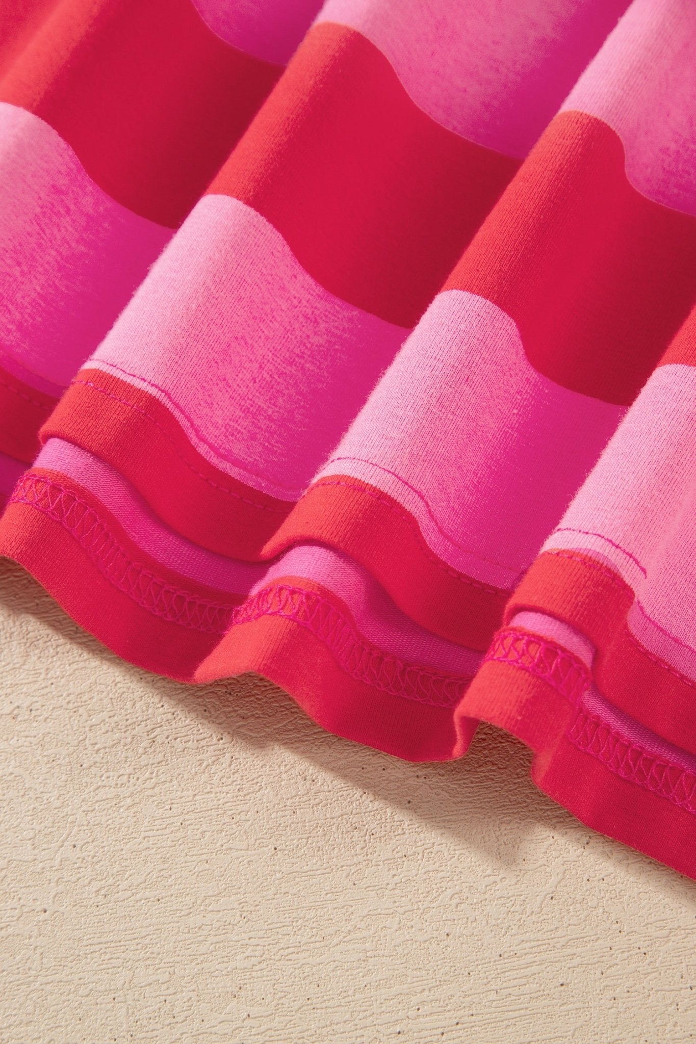 Close-up of pleated pink, magenta, and red wavy-striped fabric.