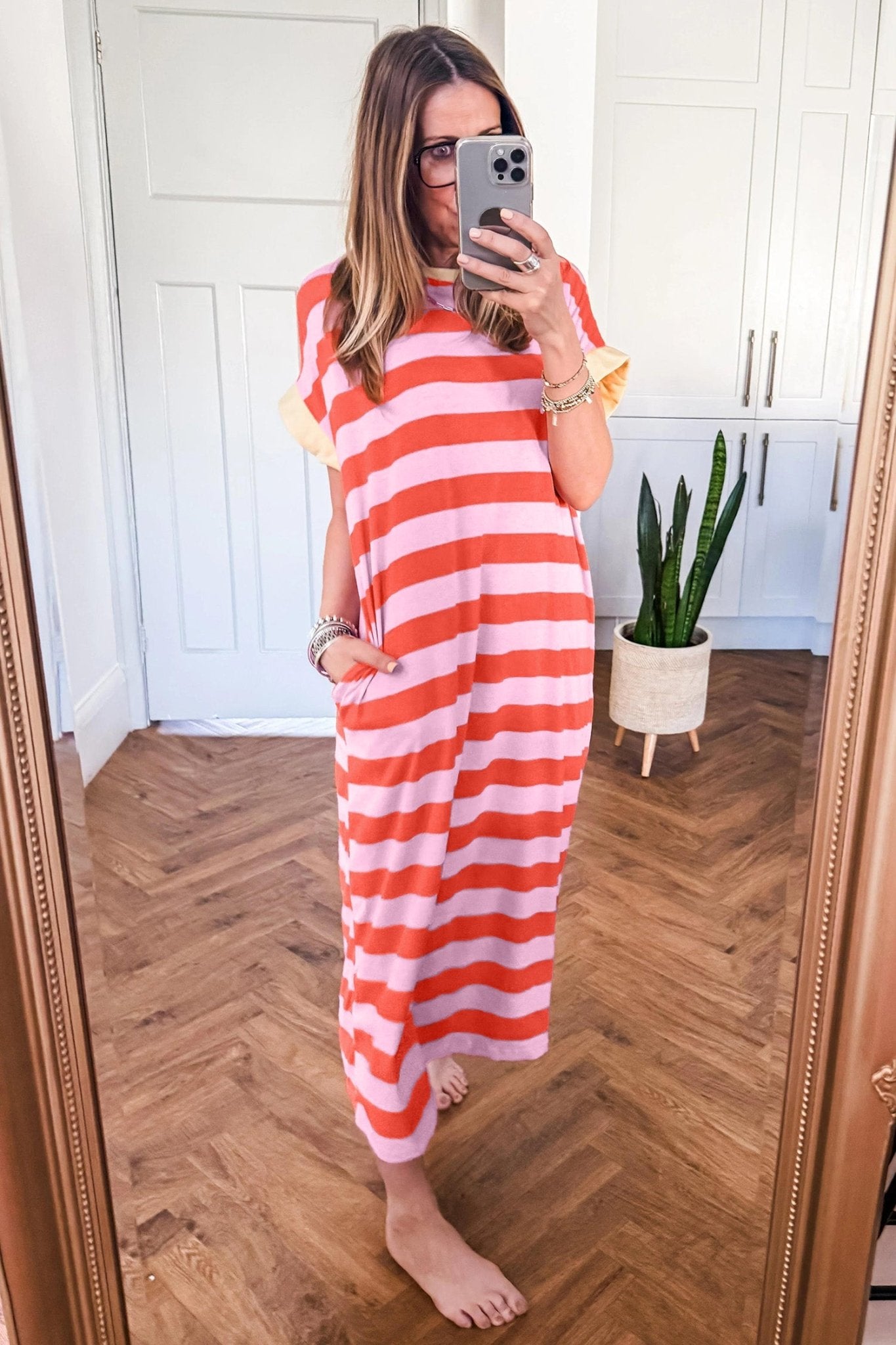 Woman taking a mirror selfie wearing a red and white striped dress in a home setting.