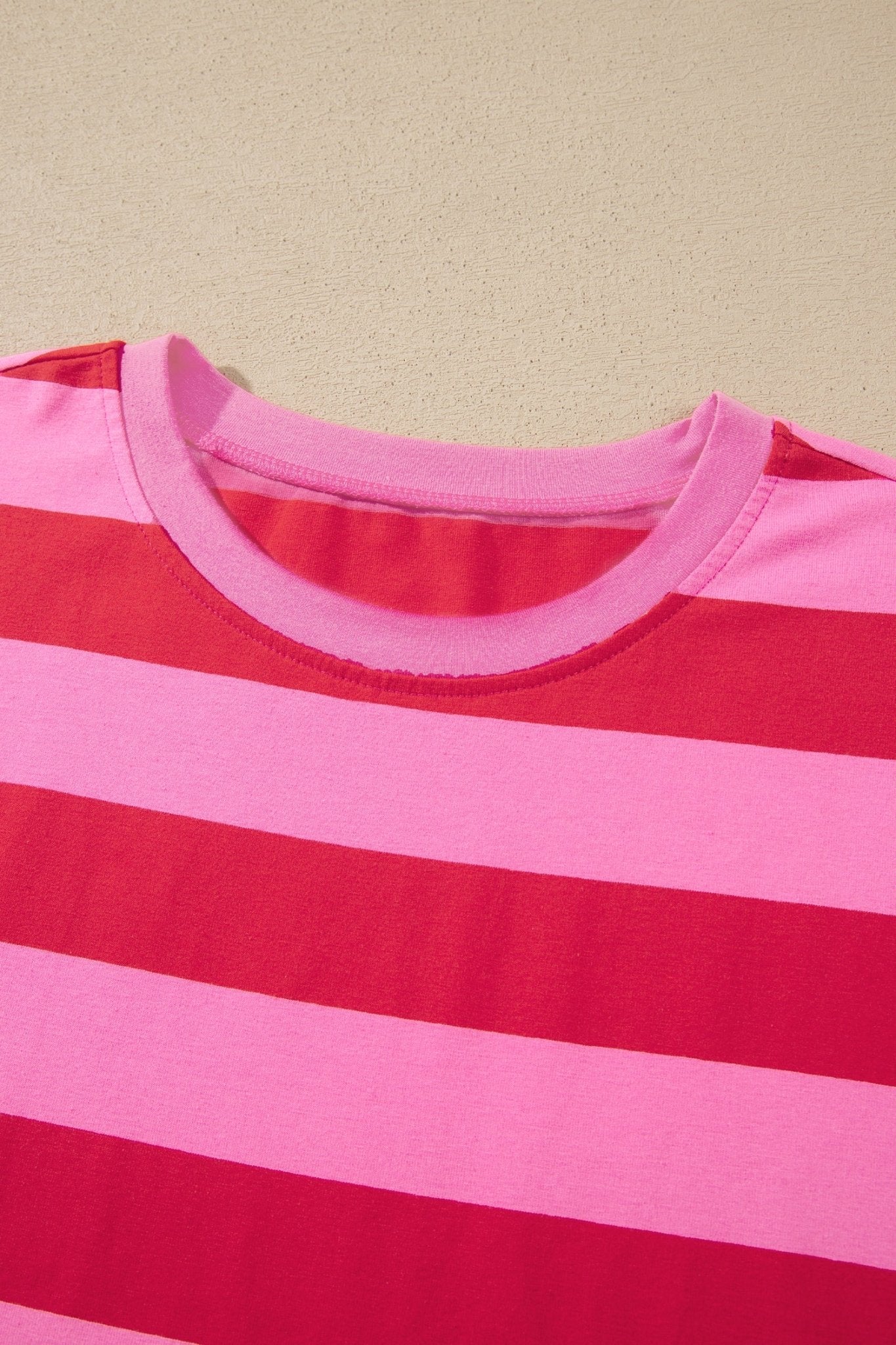 Close-up of a pink and red striped t-shirt with crew neck collar.