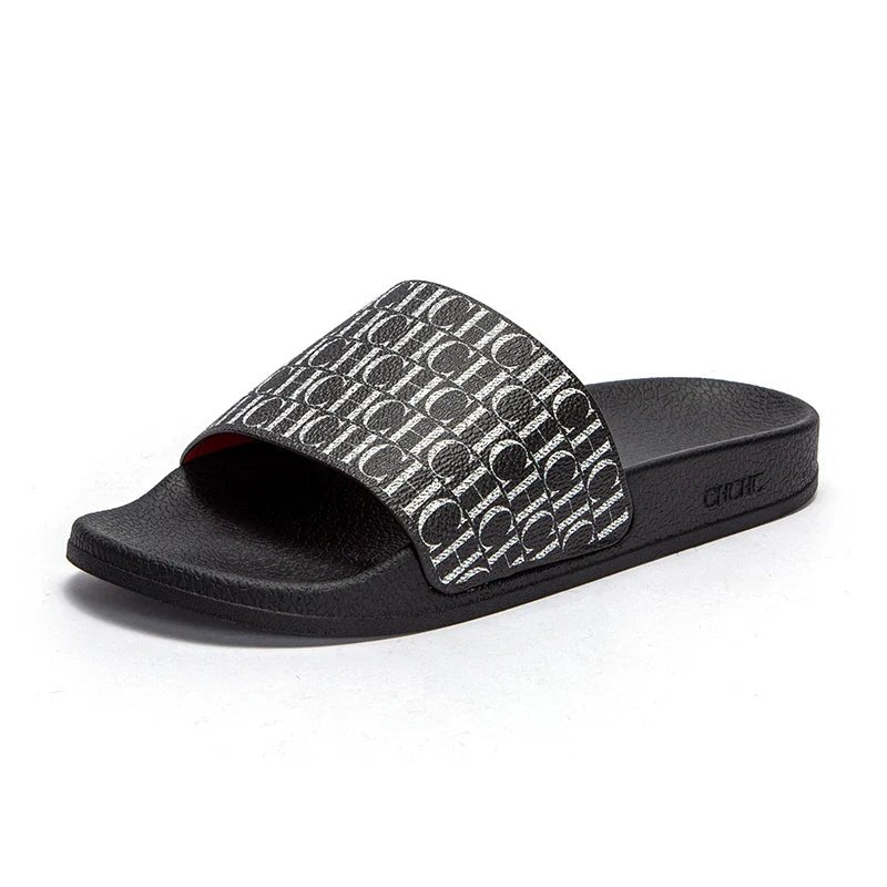Black slide sandal with patterned strap on a white background