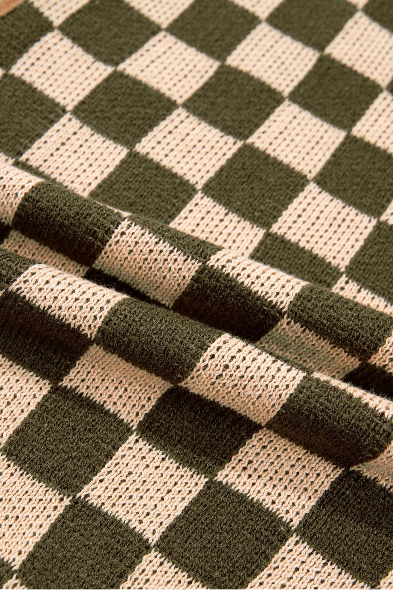 Close-up of dark olive green and cream checkerboard knit fabric with soft folds and textured detail.