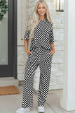 Woman wearing a black and white checkered outfit standing outside a building.