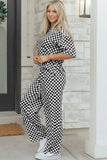 Woman wearing a black and white checkered outfit standing on a porch.