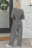 Person wearing a black and white checkered outfit standing in front of a stone wall.