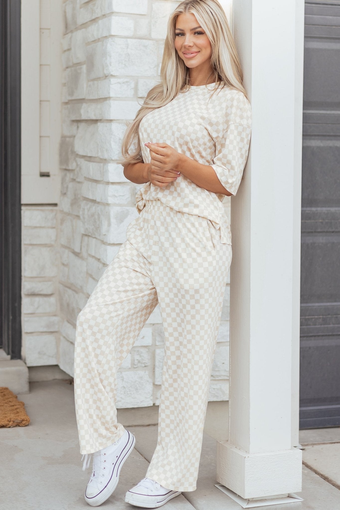 Woman wearing a white textured outfit standing against a stone wall.