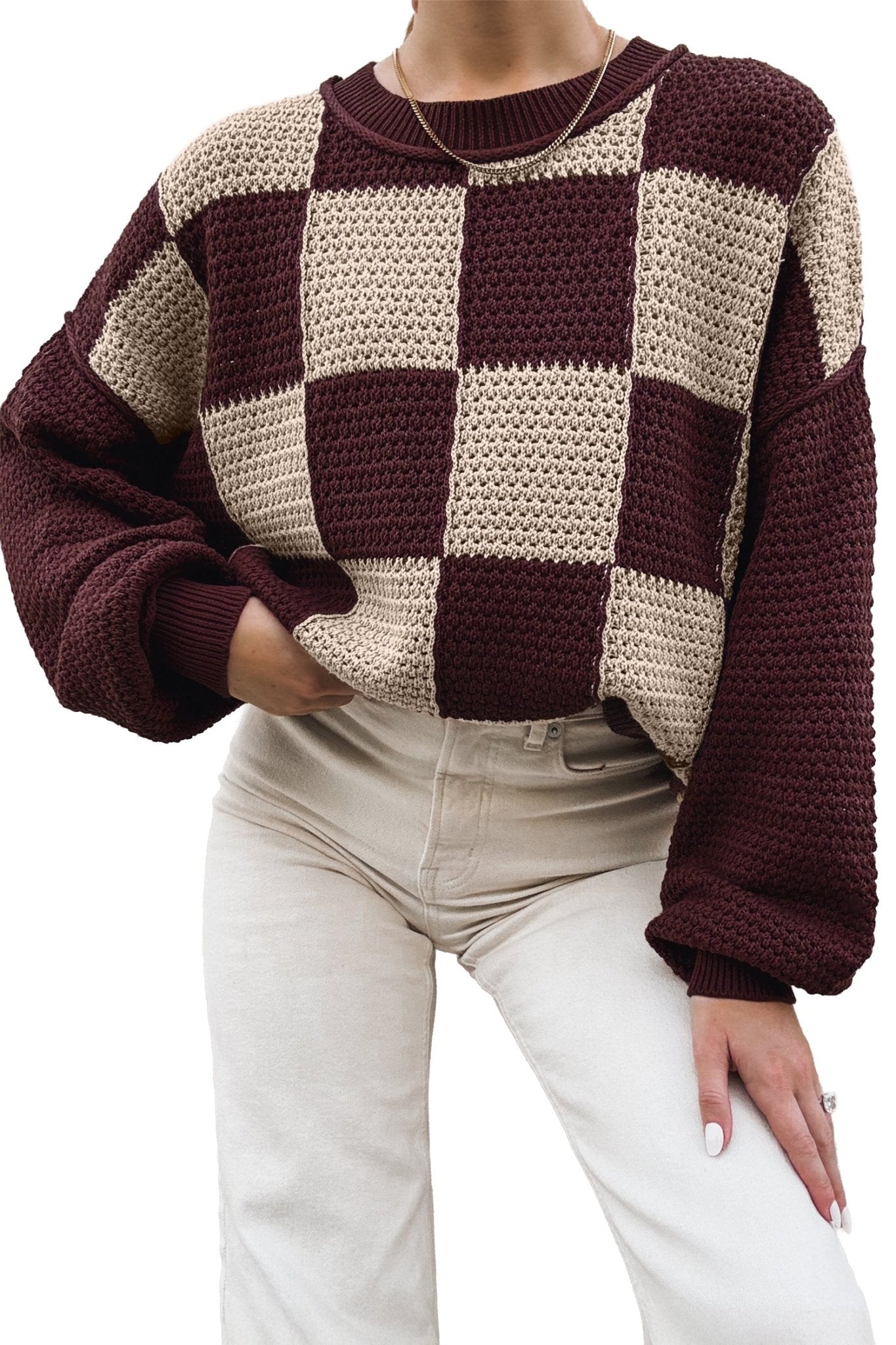 Person in chunky burgundy-cream checkered sweater with light beige pants.