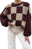 Person in chunky burgundy-cream checkered sweater with light beige pants.
