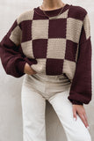Person in burgundy-cream chunky checkered sweater with light beige pants.