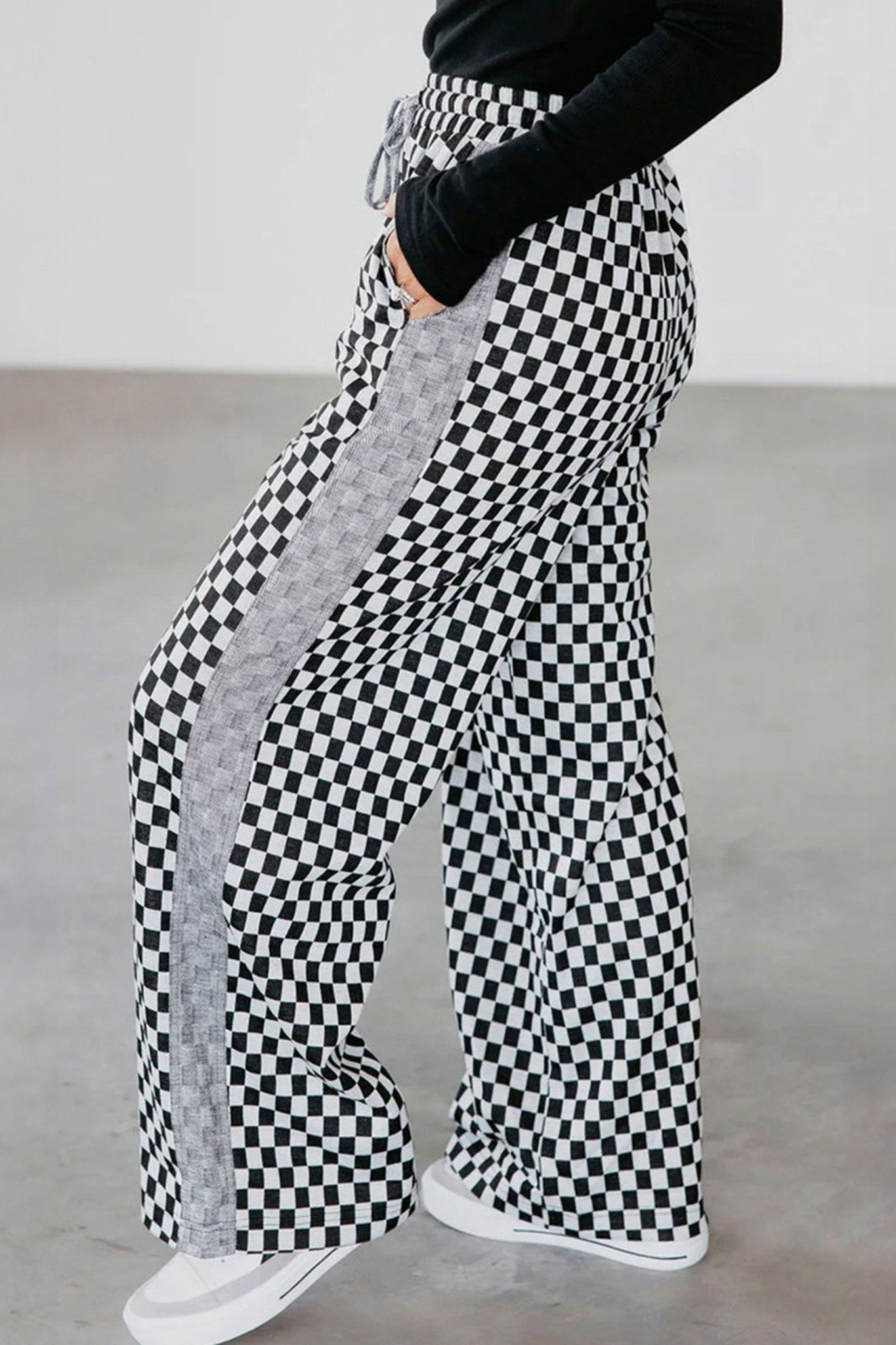 Checkered pants with gray side strip worn by a person on a plain background
