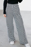 Person wearing black and white checkered pants on a plain background