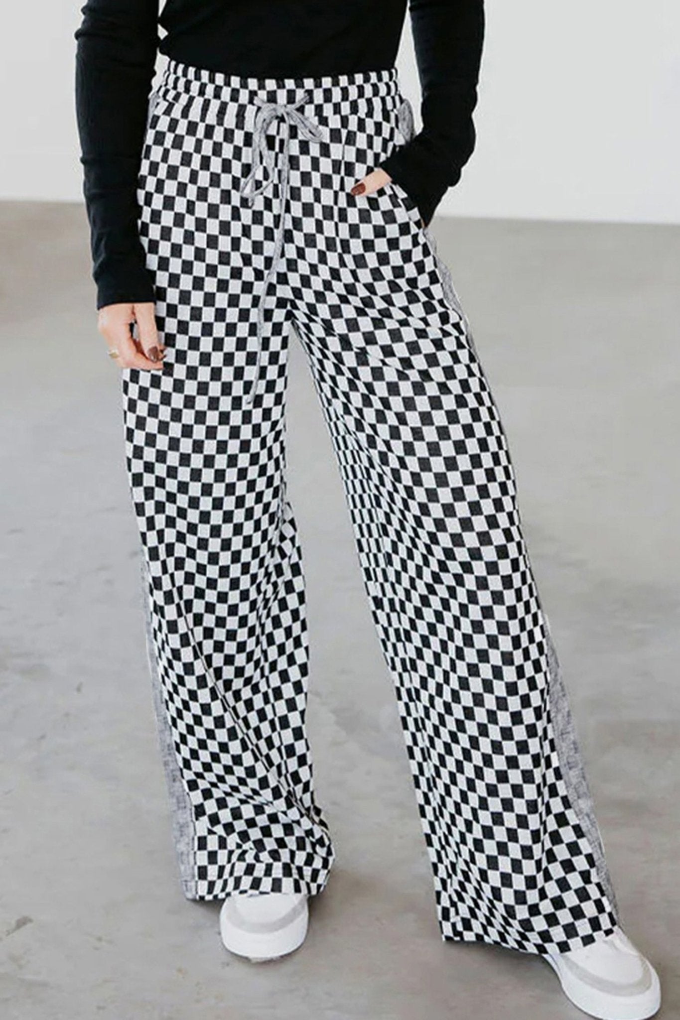 Person wearing black and white checkered pants with a plain background