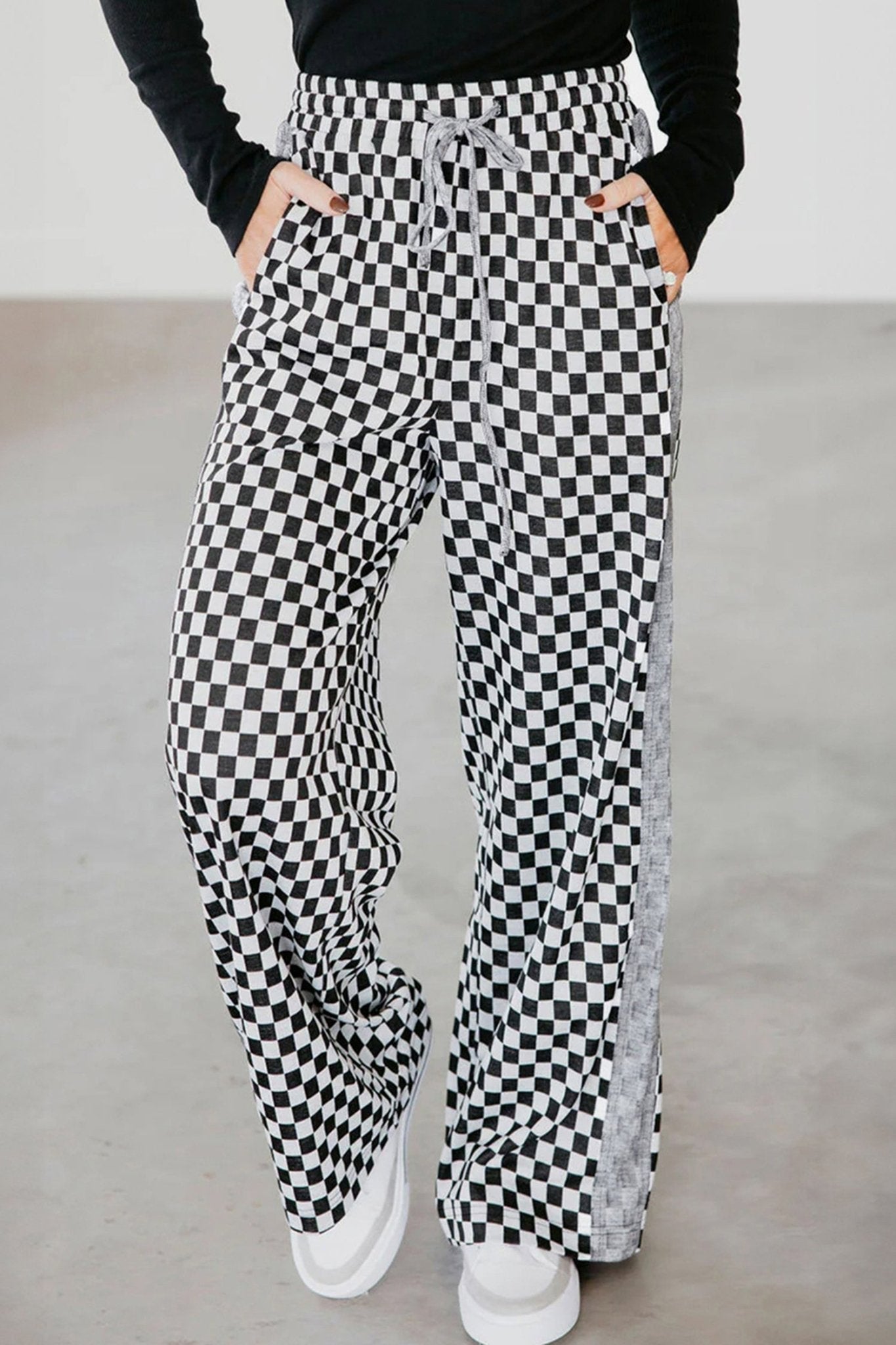 Person wearing black and white checkered pants on a plain background