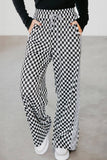 Person wearing black and white checkered pants on a plain background