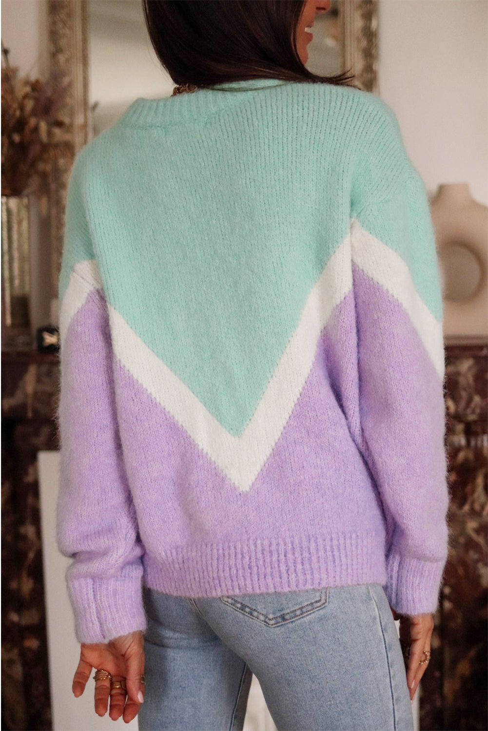 Person wearing a colorful sweater with a geometric pattern in a blurred indoor setting