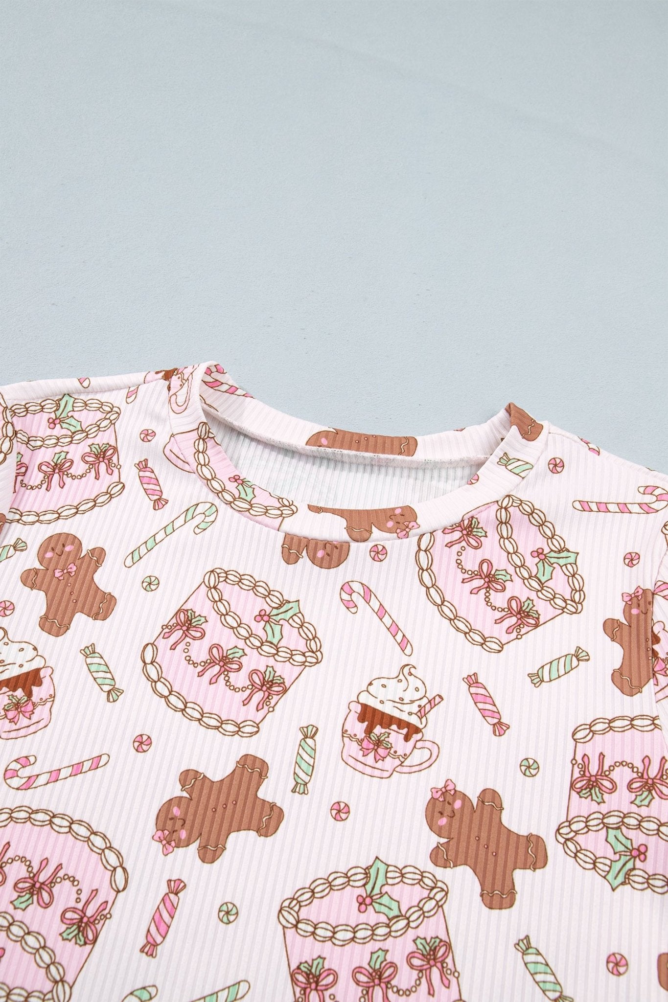 Close-up of light pink ribbed knit top with gingerbread and candy print.