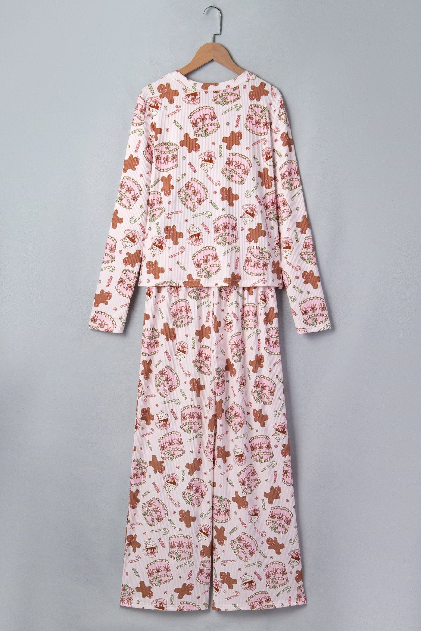 Light pink pajamas with gingerbread, cinnamon sticks, and heart print on hanger.