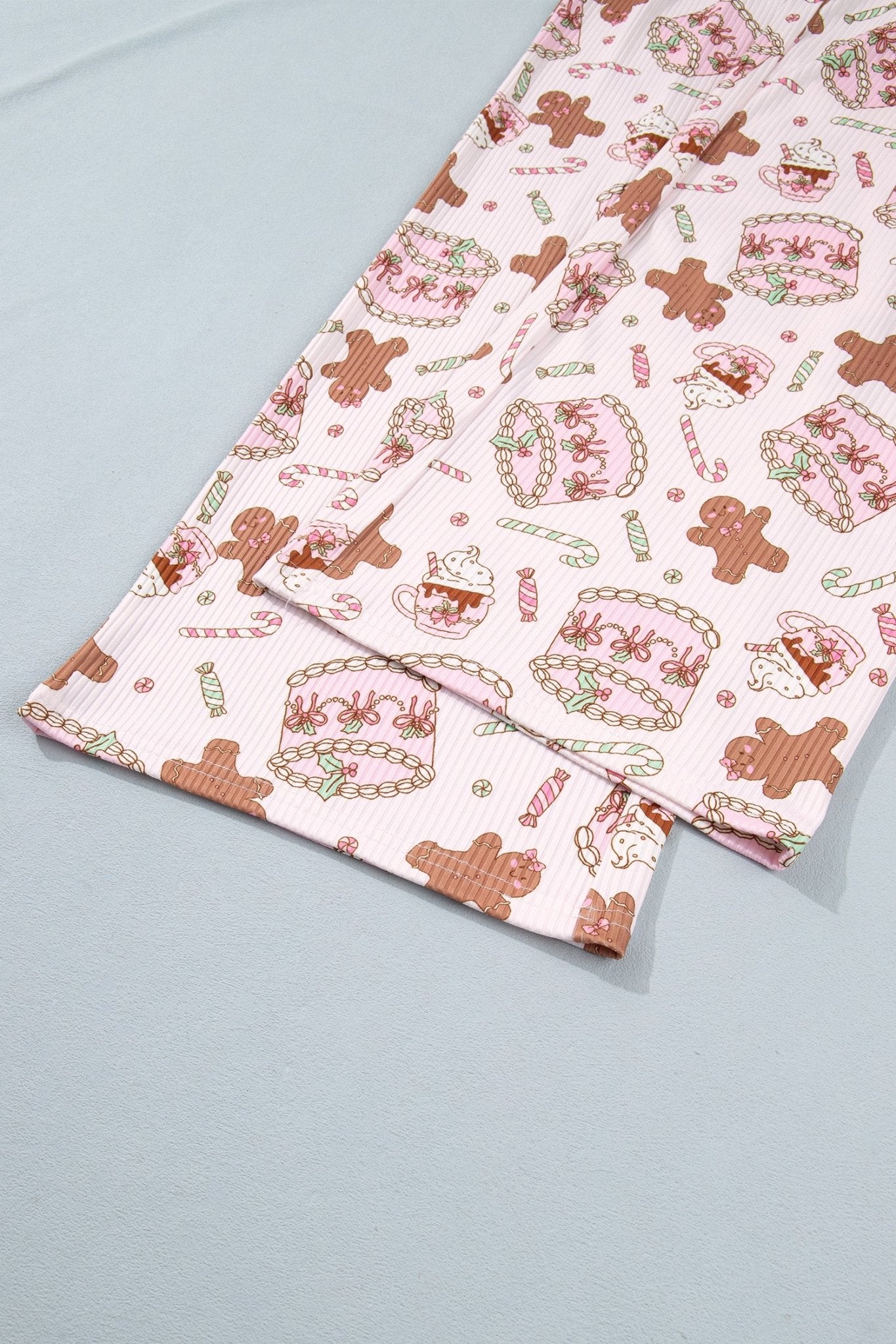 Close-up of light pink ribbed fabric with gingerbread, cupcakes, and candy canes.