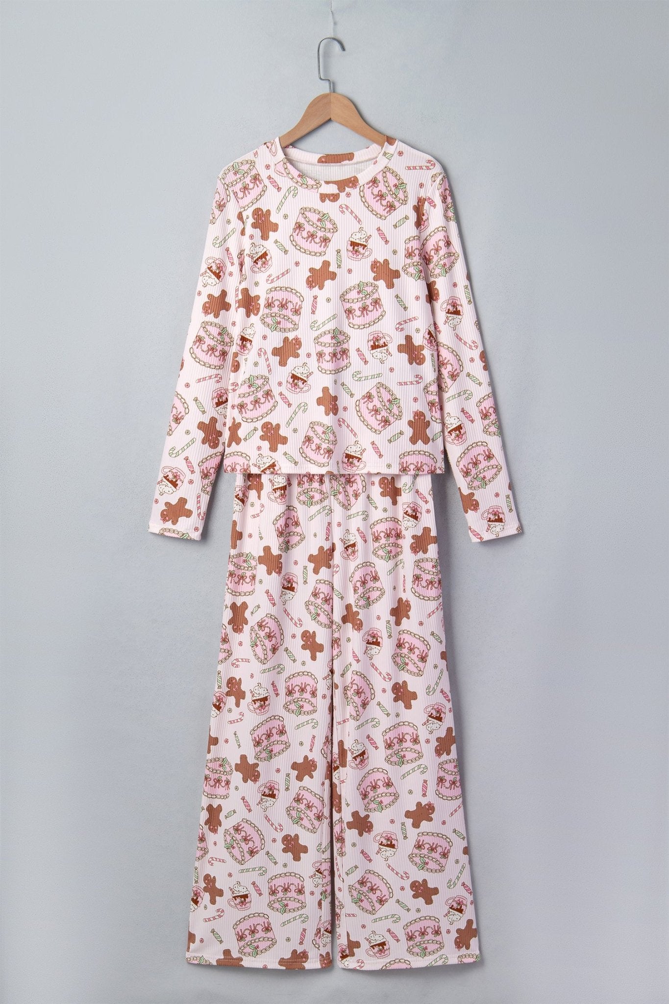 White pajamas with gingerbread, hearts, and “Candy” print on wooden hanger.