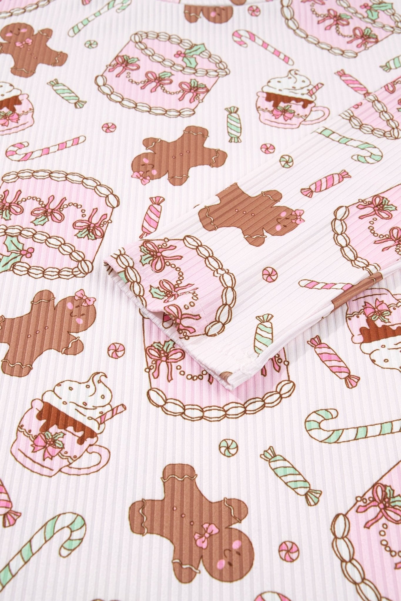 Close-up of pink ribbed fabric with gingerbread, cupcakes, candy canes, and cookies.