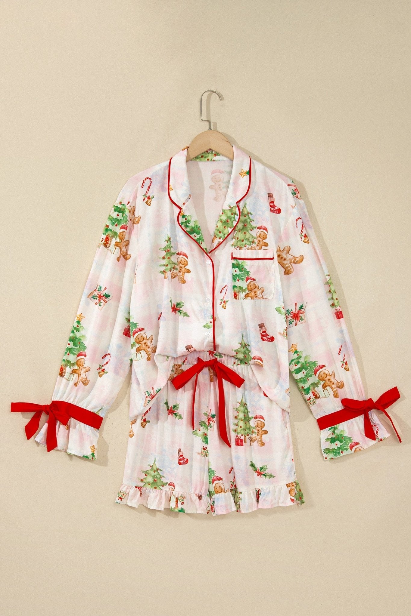 White Christmas pajama set with red trim and bow details on hanger.