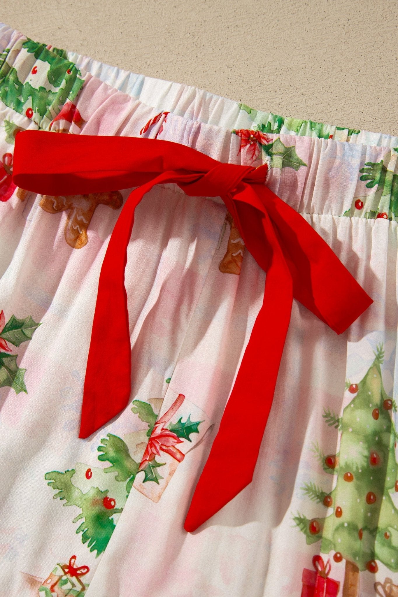 Light pink Christmas fabric with holly, gingerbread, tree, and red bow.