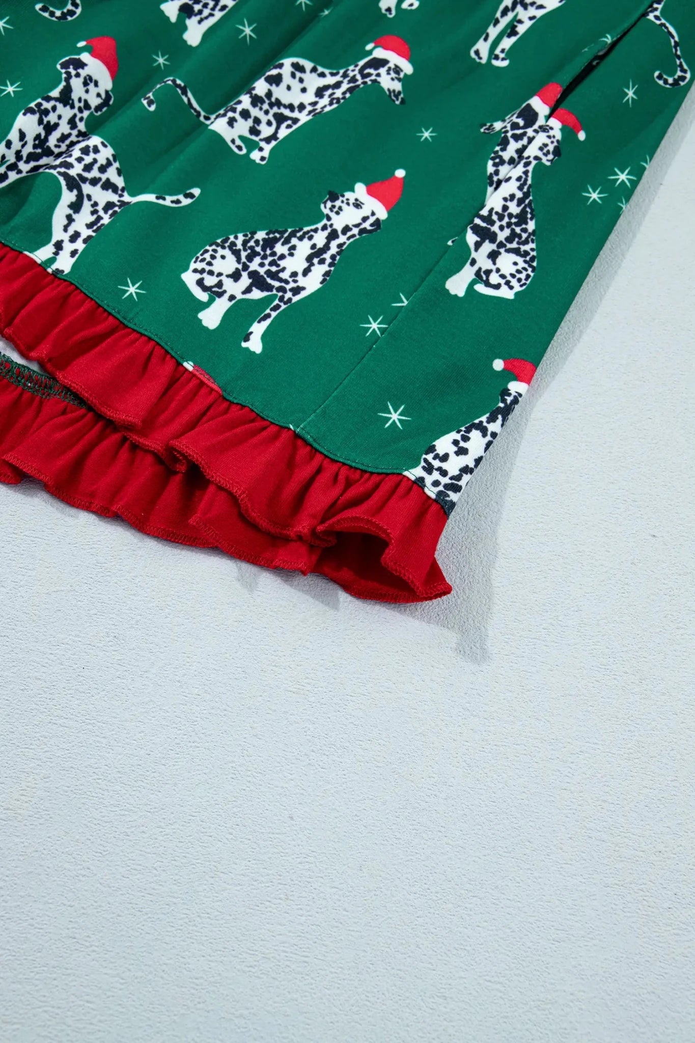 Green fabric with Dalmatian dogs in Santa hats, white stars, and red ruffled trim.