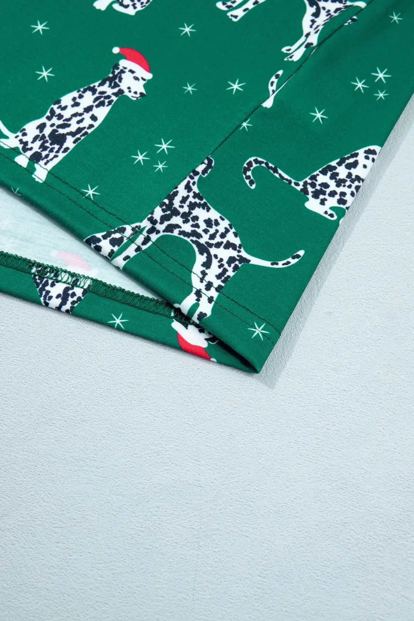 Folded green Dalmatian fabric with white stars and a red Santa hat.